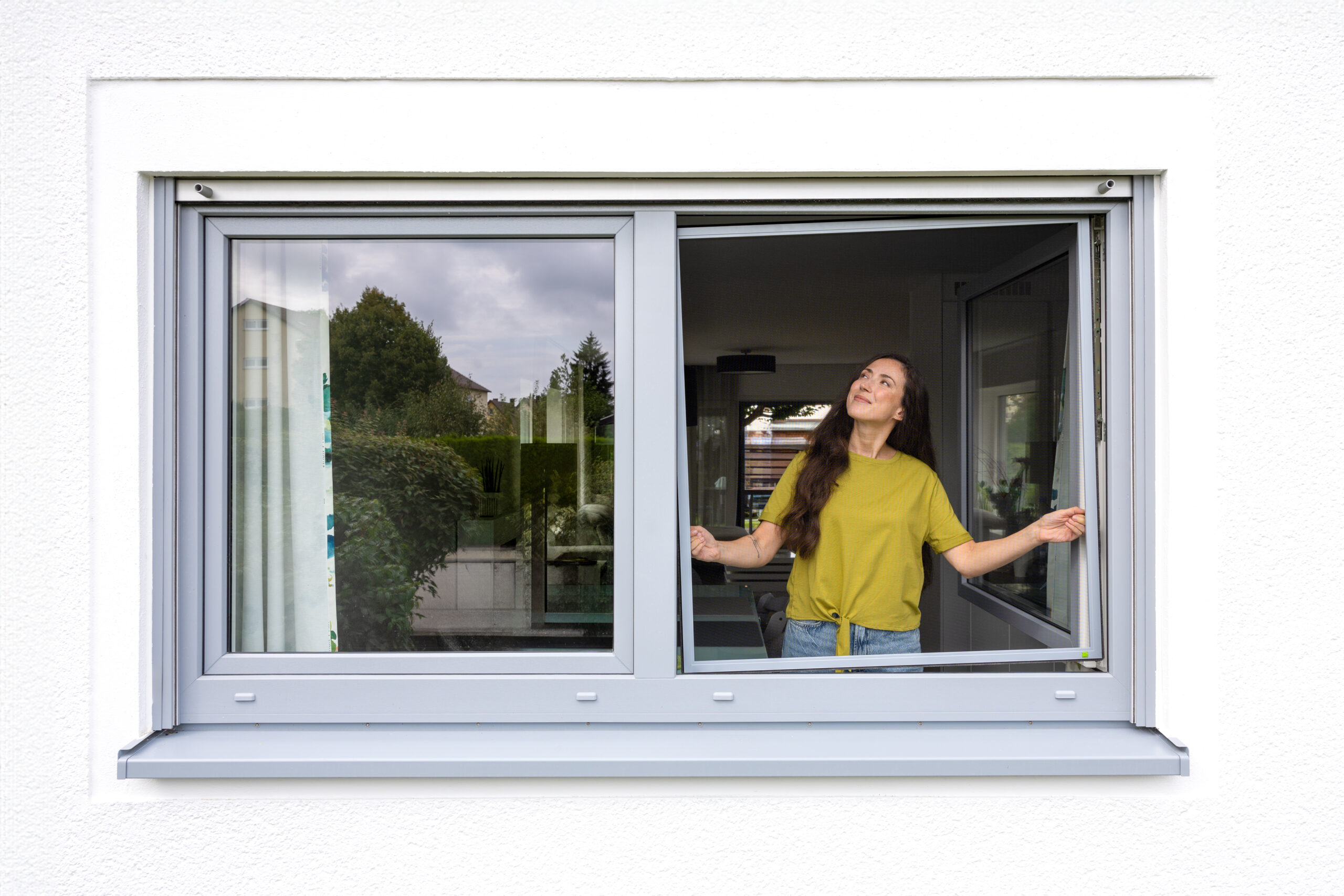 Frau öffnet Fenster mit installiertem Fliegengitter Spannrahmen einflügelig